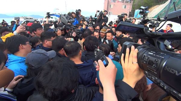 Footage of the media frenzy at the site convey the chaos and demand for answers